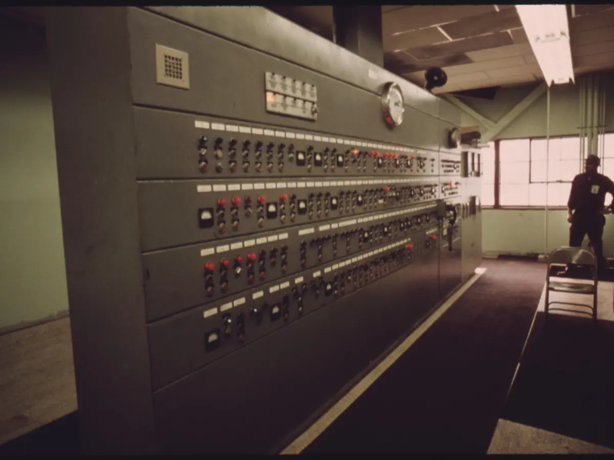 Plant control room with a wide panel of switches, dials and status lights